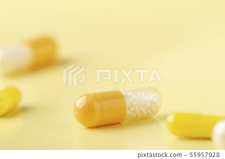A few white-yellow drug capsules on the yellow background 55957928