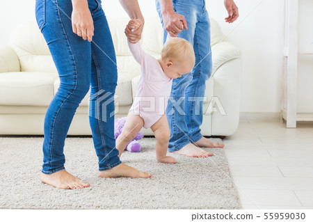 Family, children and parenthood concept - Parents teaching baby girl to walk 55959030
