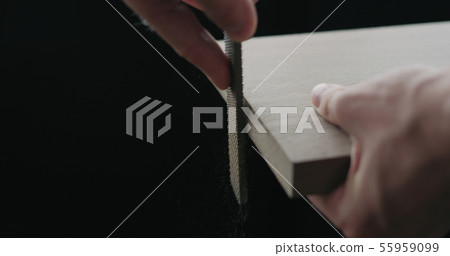 woodworker hand sanding walnut board with file 55959099