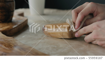 woodworker applying oil finish to olive wood scoop woodworker applying oil finish to olive wood scoop 55959187