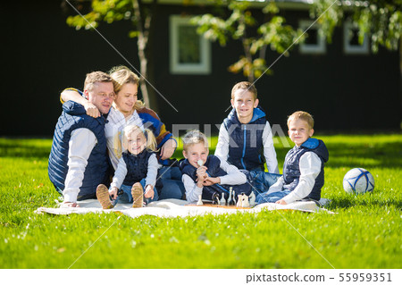 Big Family Relaxing In Green Nature. Happy family portrait on outdoor, group six people sit on grass 55959351
