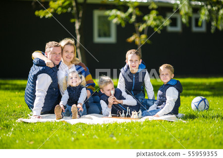 Big Family Relaxing In Green Nature. Happy family portrait on outdoor, group six people sit on grass 55959355