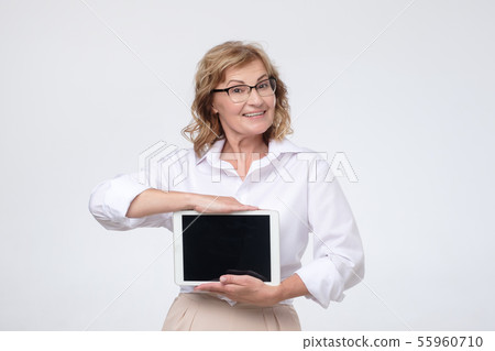 Mature caucasian woman shows a screen digital tablet. 55960710