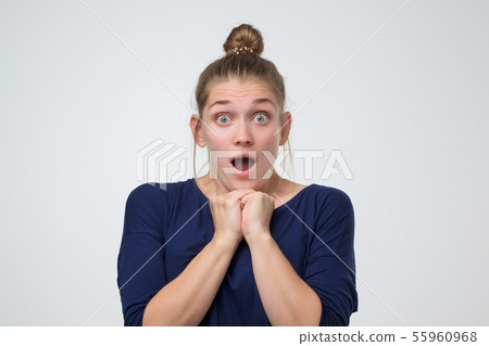 Woman with hair bun standing with open mouth shocked with the latest news. 55960968