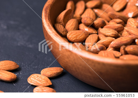 Close up. almonds in a wooden bowl on a dark background Close up. almonds in a wooden bowl on a dark background 55961053