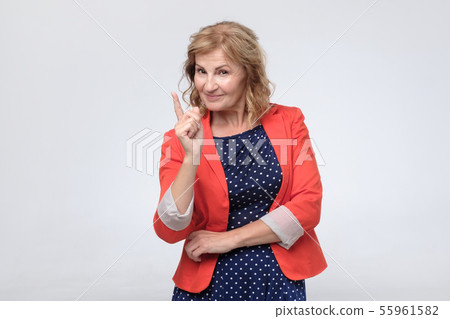 Mature woman points finger at you with a confident expression Mature woman points finger at you with a confident expression 55961582
