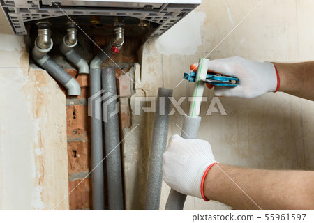 A worker is installing the gas boiler pipes. A worker is installing the gas boiler pipes. 55961597