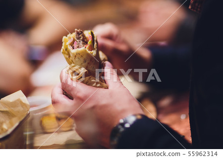 close-up of man eating doner kebab hand. close-up of man eating doner kebab hand. 55962314