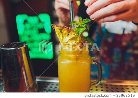 Bartender finished decorating his cocktail with mint and orange slice. Bartender finished decorating his cocktail with mint and orange slice. 55962519