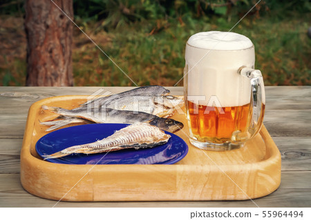 Mug of light beer and dried fish on a wooden table in a summer day outdoors - photo, image 55964494
