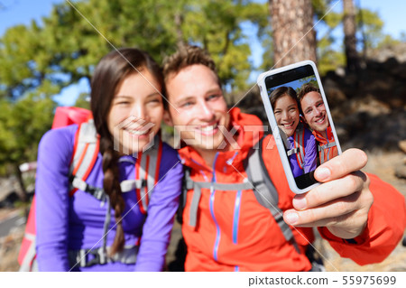 Selfie couple using smart phone camera hiking 55975699