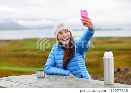 Woman outdoors using smart phone taking selfie Woman outdoors using smart phone taking selfie 55977826