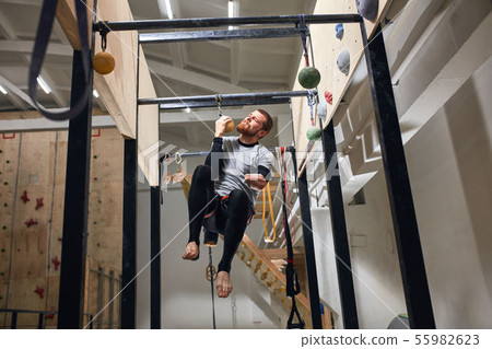 Powerful man with physical disability performing pull up exercise on one hand Powerful man with physical disability performing pull up exercise on one hand 55982623