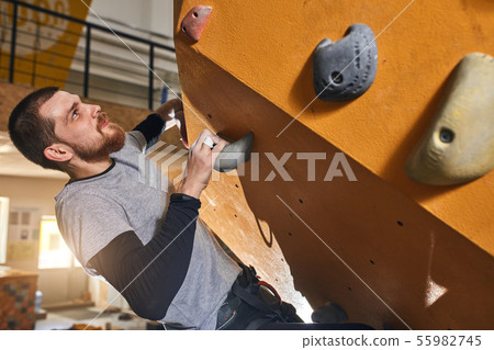Cheerful rock-climber without forearm training at indoor bouldering gym Cheerful rock-climber without forearm training at indoor bouldering gym 55982745