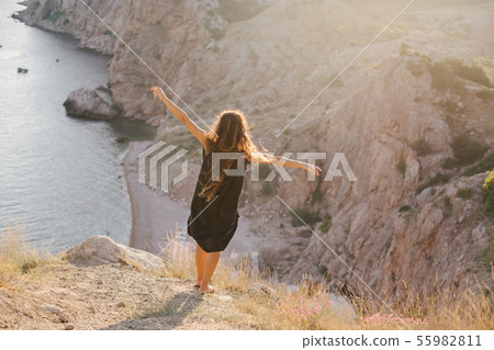 Woman with long curly hair on top of mountain. 55982811
