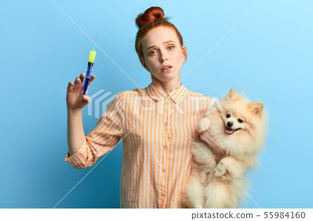 woman in striped shirt giving medicine to her pet wich has problems with health 55984160