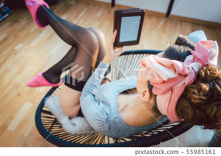 Woman wearing stocking and pink slippers reading a book at home 55985161