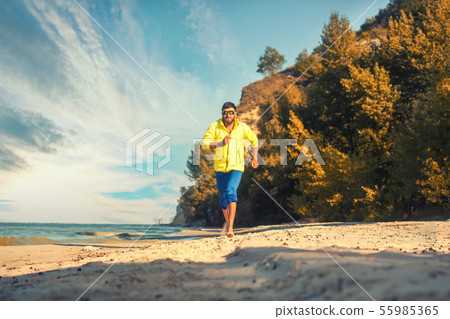 bearded athlete runs along the sandy beach. bearded athlete runs along the sandy beach. 55985365