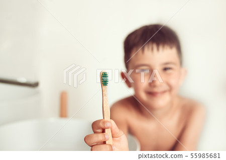 The child brushes teeth with a bamboo toothbrush. The child brushes teeth with a bamboo toothbrush. 55985681