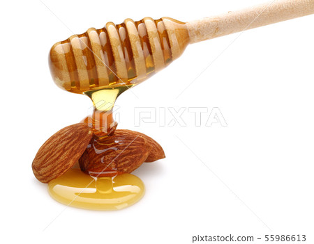 Honey dripping from dipper, on almonds isolated 55986613