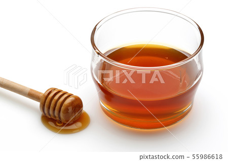 Honey dripping from dipper and honey in glass bowl Honey dripping from dipper and honey in glass bowl 55986618