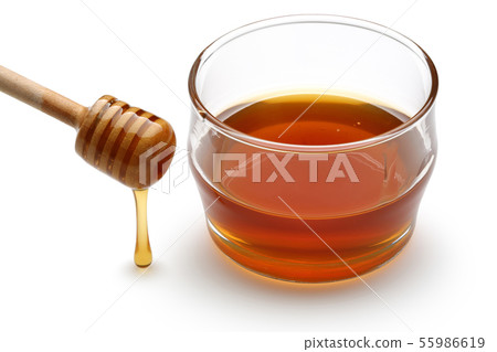 Honey dripping from dipper and honey in glass bowl Honey dripping from dipper and honey in glass bowl 55986619
