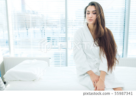 Young brunette woman in white bathrobe waiting for LPG massage session Young brunette woman in white bathrobe waiting for LPG massage session 55987341