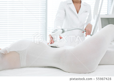 close up beauty specialist doing LPG apparatus massage on female hips 55987428