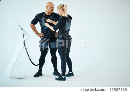 blonde female trainer helps man to attach electrode on ems suit blonde female trainer helps man to attach electrode on ems suit 55987889