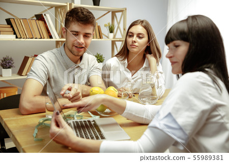 Smiling nutritionist showing a healthy diet plan to patient 55989381