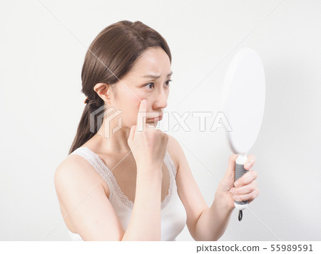 A woman troubled watching a mirror A woman troubled watching a mirror 55989591