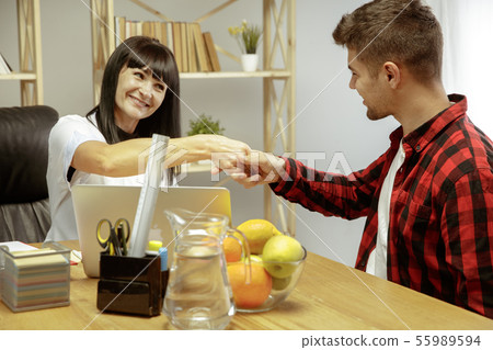 Smiling nutritionist showing a healthy diet plan to patient Smiling nutritionist showing a healthy diet plan to patient 55989594