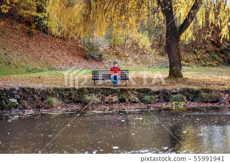 Lonely senior man sitting on bench by lake in nature, looking at camera. Lonely senior man sitting on bench by lake in nature, looking at camera. 55991941