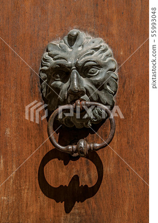 Face-shaped knocker on wooden door Face-shaped knocker on wooden door 55993048