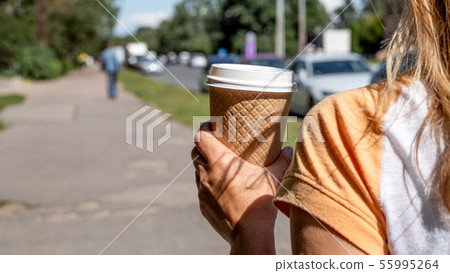 Holding takeaway coffee cup on the street Holding takeaway coffee cup on the street 55995264