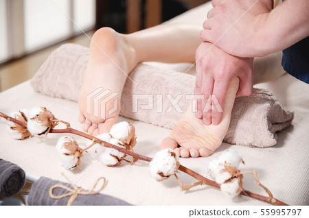 Close-up spa salon male physiotherapist doing foot massage to a young girl. Concept for foot health Close-up spa salon male physiotherapist doing foot massage to a young girl. Concept for foot health 55995797
