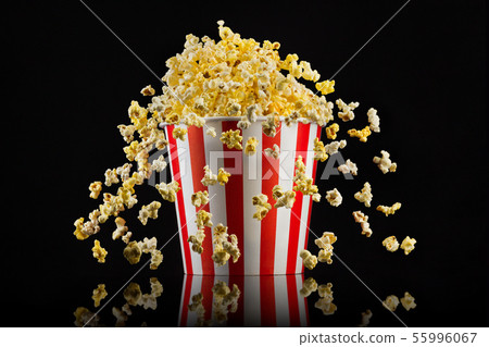 Flying popcorn from striped bucket isolated on black background 55996067