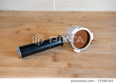 portafilter with temping ground coffee on wooden table portafilter with temping ground coffee on wooden table 55996368