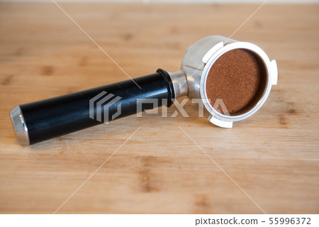portafilter with temping ground coffee on wooden table 55996372