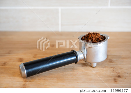 Filter holder with ground coffee on wooden table Filter holder with ground coffee on wooden table 55996377