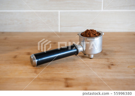 Filter holder with ground coffee on wooden table 55996380