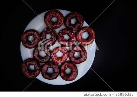 assorted donuts with chocolate frosted, pink glazed and sprinkles donuts on black background 55996383