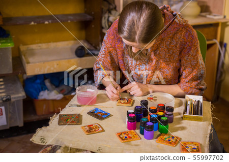 Professional woman potter painting ceramic souvenir magnet in potter Professional woman potter painting ceramic souvenir magnet in potter 55997702