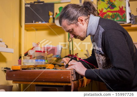 Skinner making decorative details on leather playing field 55997726