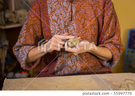 Woman potter making ceramic souvenir penny whistle in pottery workshop 55997770