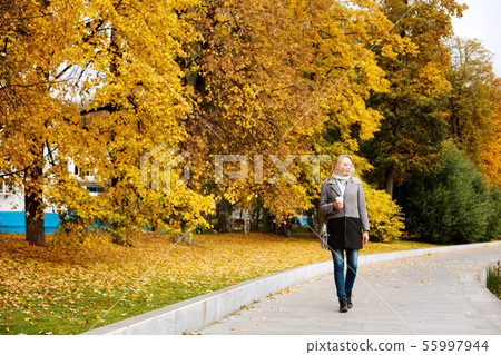 Elegant confident woman walking in the city park 55997944