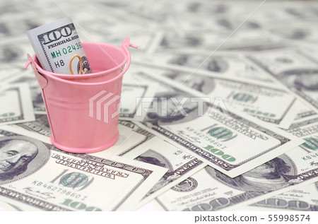 A bundle of US dollars in a metal pink bucket on a 55998574