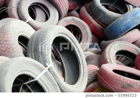 A picture of many old used tires left on a waste A picture of many old used tires left on a waste 55998723