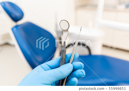 The hand of the dentist in the glove holds tool probe and mirror. . Stomatological instrument in the 55999851
