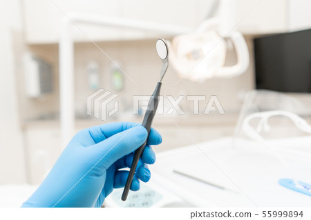 The hand of the dentist in the glove holds tool mirror. Stomatological instrument in the dentist 55999894